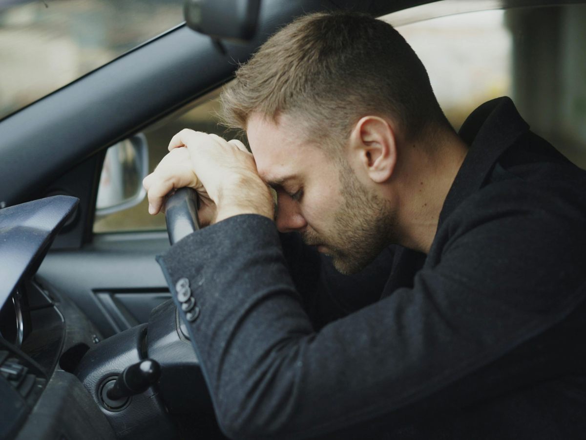 Erschöpfter Autofahrer lehnt den Kopf ans Lenkrad