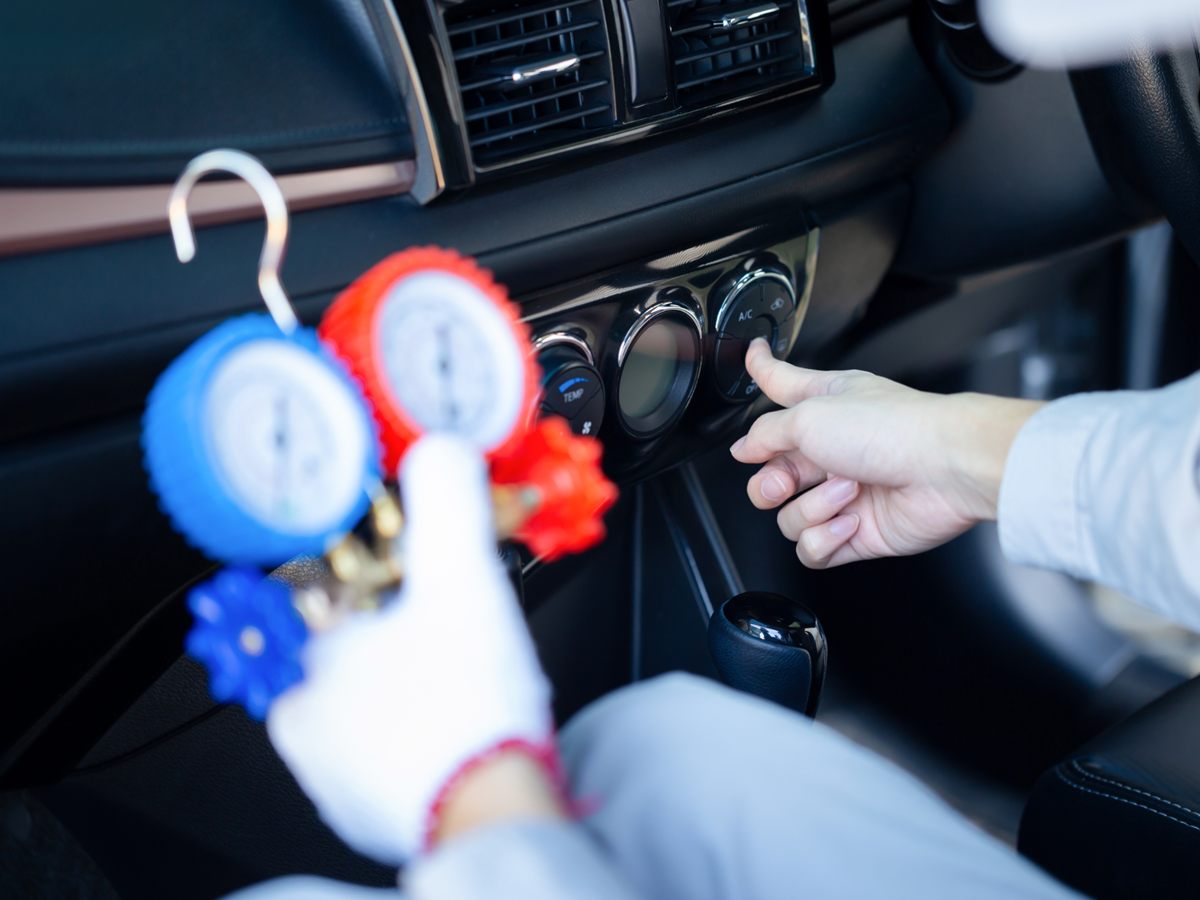 Monteur mit Manometern prüft die Klimaanlage und schaltet sie im Auto ein