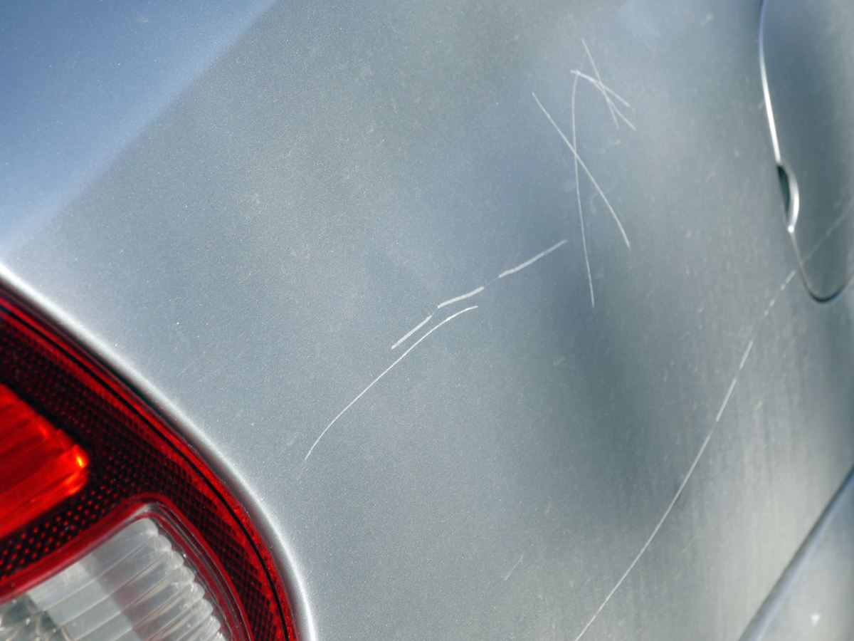 Kratzer im silbernen Lack neben der Rückleuchte eines Autos