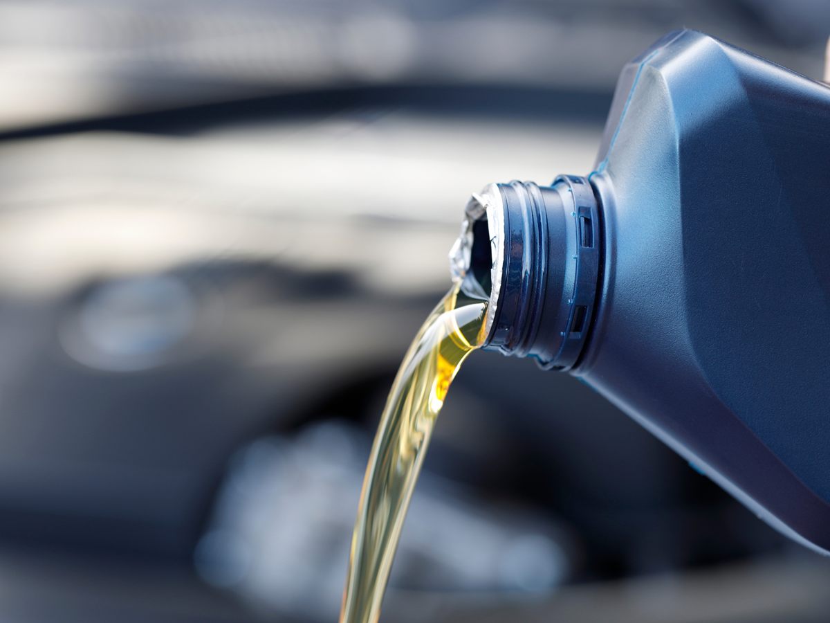 Goldgelbes Motoröl fließt aus einer Ölflasche