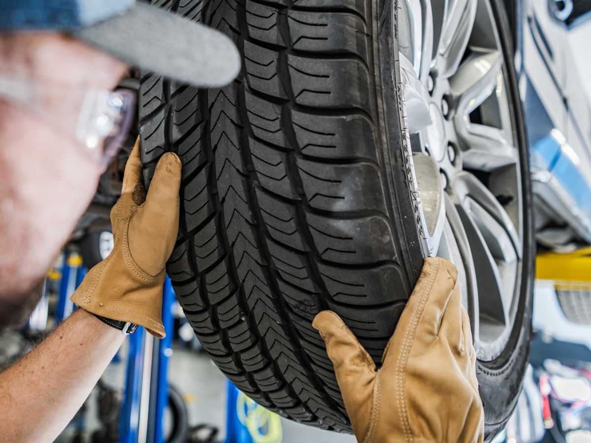 Mechaniker mit Lederhandschuhen montiert einen Reifen auf der Hebebühne